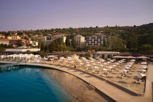una piscina con ombrelloni e sedie accanto a un resort di Hotel Kempinski Palace Portorož a Portoroz