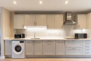 a kitchen with white cabinets and a washer and dryer at Newly Refurbished Home Short Drive to Bath Centre in Bath