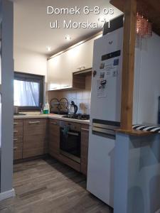 a kitchen with white appliances and wooden cabinets at Domki Morska in Rewa