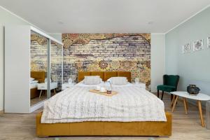 a bedroom with a large bed and a brick wall at Komfortowe Studio w Centrum Bytomia Blisko Rynku by Noclegi Renters in Bytom