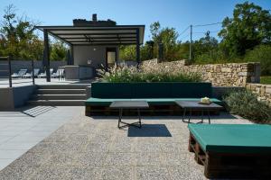 a patio with a green bench and two tables at Villa Telma in Kostrčani - Haus für 8-10 Personen in Kostrčani