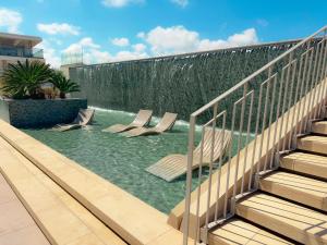 a swimming pool with chairs in front of a waterfall at QAWRA Palace Resort & SPA in St Paul's Bay