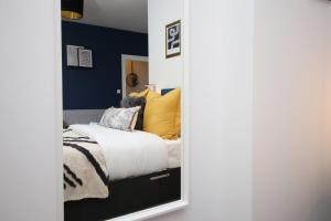 Un dormitorio con una cama con almohadas amarillas. en Minster House by Tŷ SA, en Cardiff