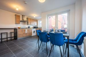 a kitchen and dining room with a table and blue chairs at Atlanta's Residence by Tŷ SA in Newport