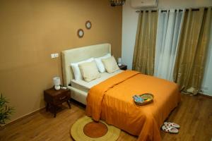una camera da letto con un letto con una coperta arancione di La Parenthèse T2 au Vallon près Rue des Jardins a Abidjan