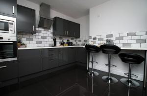 a kitchen with two bar stools and a microwave at Stunning sea views - Barry's Retreat by Tŷ SA in Barry +58 photos