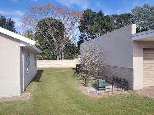 ein Hinterhof eines weißen Gebäudes mit einem Zaun in der Unterkunft Cornelia Place in Sunridge Park