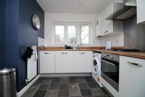 a kitchen with white cabinets and a dishwasher at Buxton Way by Tŷ SA - 3 bedroom house in Royal Wootton Bassett +16 photos