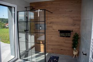 a shower in a bathroom with a wooden wall at Vila Altura- Luxury Hiltop Retreat with Panoramic View & Teracce in Rogaška Slatina