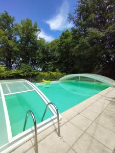 a swimming pool with blue water and trees at Gîte Lou Mas dals plats in Gelle