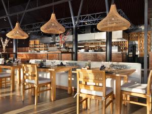 塞米亚克Grand Seminyak Lifestyle Boutique Bali Resort的餐厅设有木桌、椅子和吊灯
