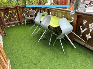 a table and chairs on a balcony with green grass at MAISON DES VIGNES- TROQUAÏROU et BECCA MOTTA in Brides-les-Bains