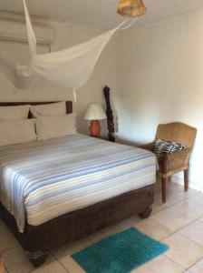 1 dormitorio con 1 cama con lámpara y silla en Tabonina Guesthouse, en Livingstone