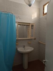 La salle de bains est pourvue d'un lavabo et d'un rideau de douche bleu. dans l'établissement Casa Nettuno, à Lido Conchiglia