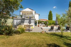 a house with a patio with chairs and umbrellas at Holiday home Dioniza by Villsy in Gajana