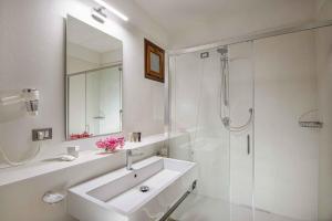 a white bathroom with a sink and a shower at Hotel Baia Imperiale in Campo nell'Elba