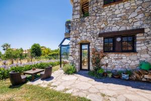 a stone building with a bench and a table at Maison Canorgues in Tourrettes-sur-Loup
