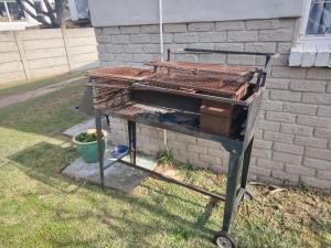 einen Grill im Gras neben einem Gebäude in der Unterkunft Cornelia Place in Sunridge Park