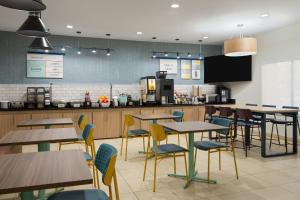a restaurant with tables and chairs and a kitchen at Garner Hotel Aiken South by IHG in Aiken