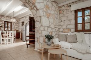 a living room with a white couch and a stone wall at Villa Boscheto Pente in Agios Leon