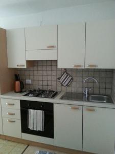 a kitchen with white cabinets and a stove and a sink at Casa Simion in Mezzano