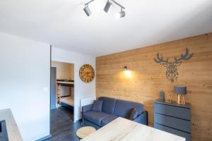 ein Wohnzimmer mit einem blauen Sofa und einer Uhr an der Wand in der Unterkunft Le Prorel appartement au pied du télécabine in Briançon