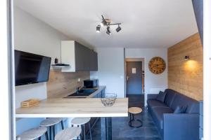 ein Wohnzimmer mit einer blauen Couch und einer Küche in der Unterkunft Le Prorel appartement au pied du télécabine in Briançon + 26 Fotos