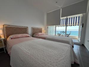 two beds in a bedroom with a view of the ocean at Tahití9H in El Campello