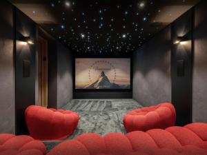 a cinema room with red chairs and a screen at Chalet Ours Rouge - OVO Network in Le Grand-Bornand
