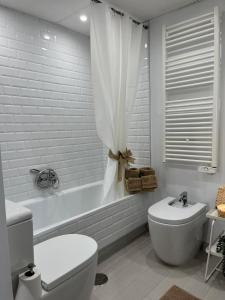 a white bathroom with a toilet and a tub and a sink at Tahití9H in El Campello