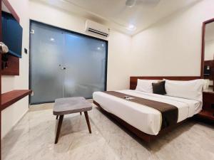 a bedroom with a large bed and a stool in it at Hotel Aqua in Rajkot