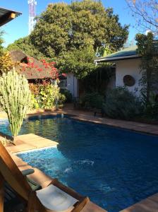 uma piscina com duas espreguiçadeiras ao lado de uma casa em Tabonina Guesthouse em Livingstone