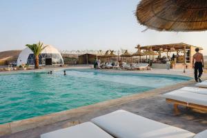 a pool at a resort with people in the water at Agafay Desert in El Karia