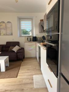 a kitchen and living room with a refrigerator and a couch at Appart au calme en rez-de-jardin in La Terrasse