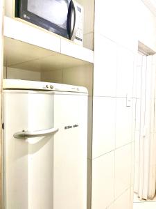a microwave on a shelf above a refrigerator at Kitinete com ótima localização in Santos