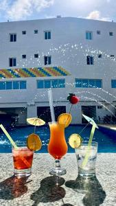 three cocktails sitting on a table near the water at Hotel Aventura Suites Tucacas in Tucacas +56 photos