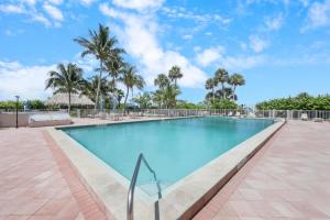 a large swimming pool with palm trees in the background at SW facing beachfront condo with sweeping ocean views in Marco Island