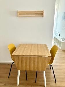 a wooden table with two yellow chairs in a room at Casa Nina in Villasanta