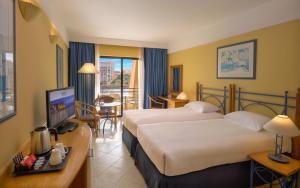 a hotel room with two beds and a television at Verdi St George's Bay Marina in St. Julianʼs +38 photos