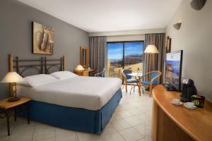 a hotel room with a bed and a desk with a television at Verdi St George's Bay Marina in St. Julianʼs