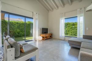 Una sala de estar con un sofá y un televisor y ventanas. en Villa Miau, en Sagres