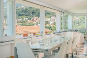 a dining room with a glass table and white chairs at Luxury Levaina Villa Sleeps 8 on the Amalfi Coast in Positano