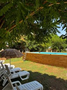 two chairs and an umbrella next to a swimming pool at Agriturismo Curatola in Spilinga