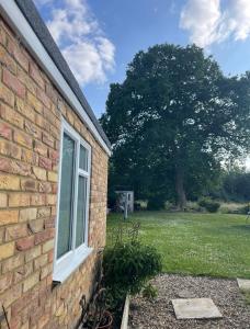 a window on the side of a brick house with a tree at Shangri-La in Chesham