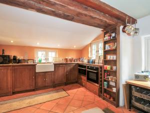eine große Küche mit Holzschränken und einem Regal in der Unterkunft Rose Cottage in Okehampton