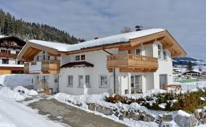 a house with a balcony in the snow at Appartement Angelika in Brixen im Thale