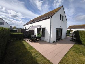 een wit huis met een tafel en een paraplu bij Maxent aan zee in Middelkerke