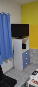 a room with a tv on a desk with a blue curtain at Yellow Hostel in São Paulo