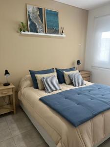 een groot bed met blauwe kussens in een slaapkamer bij Departamento Venthos in Puerto Madryn