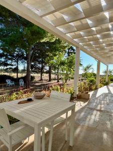 a white table and chairs under a white pergola at Arneo Rooms in Torre Lapillo